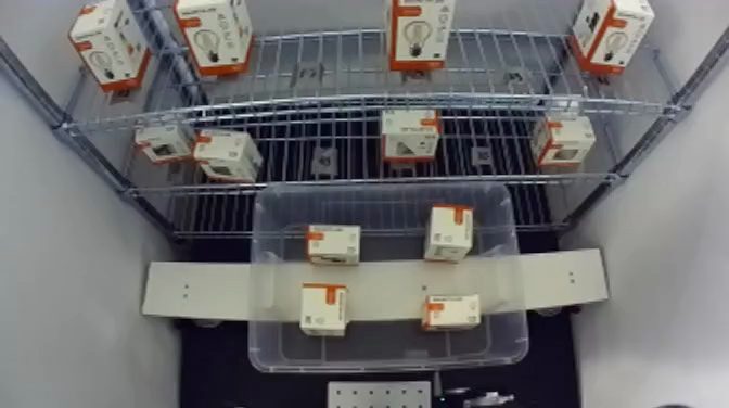 The robot, the container of boxes and the two-level shelf, seen from the fixed camera
